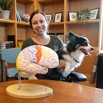 erin hecht holding a dog in front of a model of a brain
