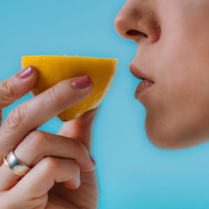 Anosmia or smell blindness, loss of the ability to smell, one of the possible symptoms of covid-19, infectious disease caused by corona virus. Woman Trying to Sense Smell of a Lemon