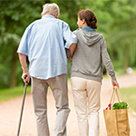 a younger person helping an elderly person walk