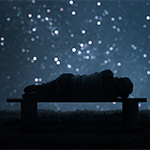 a person laying down on a bench at night