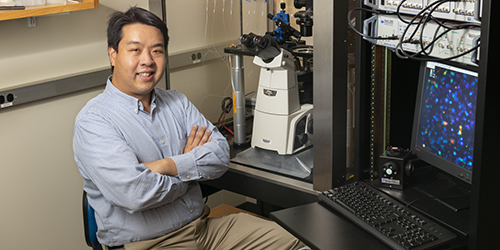 Isaac Chiu sitting at a microscope