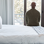 Rearview shot of a mature man looking through a window in a bedroom at home