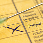 a syringe held over a piece of paper with "shingles" marked with an x.