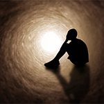 a silhouette of a person sitting down with their face in their hands.