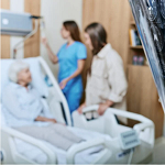an elderly woman in a hospital bed with 2 nurses looking after her