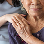 a nurse placing her hand on an elderly woman's shoulder
