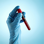 a gloved hand holding a test tube that is filled with blood