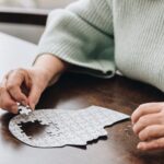 a senior woman putting together a puzzle of a human head