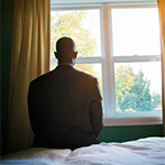 a person sitting on a bed and looking out the window