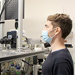 Vlad Susoy in front of a tacking microscope measuring brain activity in behaving C. elegans nematodes