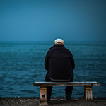 a man sitting on a bench looking out to the ocean