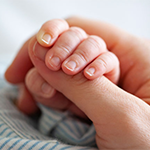 close up of a baby's hand holding an adult's finger