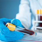 a gloved hand holding a vial of blood