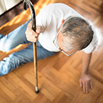 an elderly man using a cane to help himself up