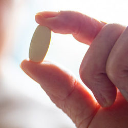 hand holding a white pill