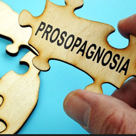 a hand holding a puzzle piece with the word "prosopagnosia" printed on it