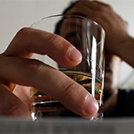 close up of a man's hand holding a shot glass