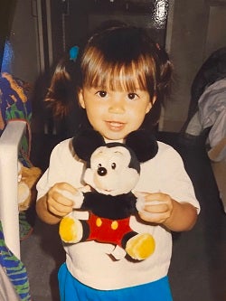 a young child holding a mickey mouse doll