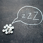 pills on a black background with a speech bubble saying 'zzzz' written in chalk.