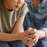 a woman comforting another woman