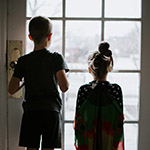 two children looking through a glass door
