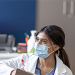 a female doctor wearing a surgical mask and writing on a notepad