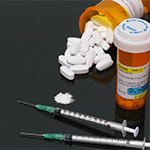 2 bottles of opiates and 2 syringes on a black background