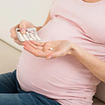 a pregnant woman holding a pill