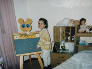 Sofia standing in front of a blackboard as a child