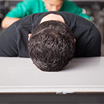 a person sleeping with their head on a desk