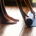 close up of a person rolling up a yoga mat